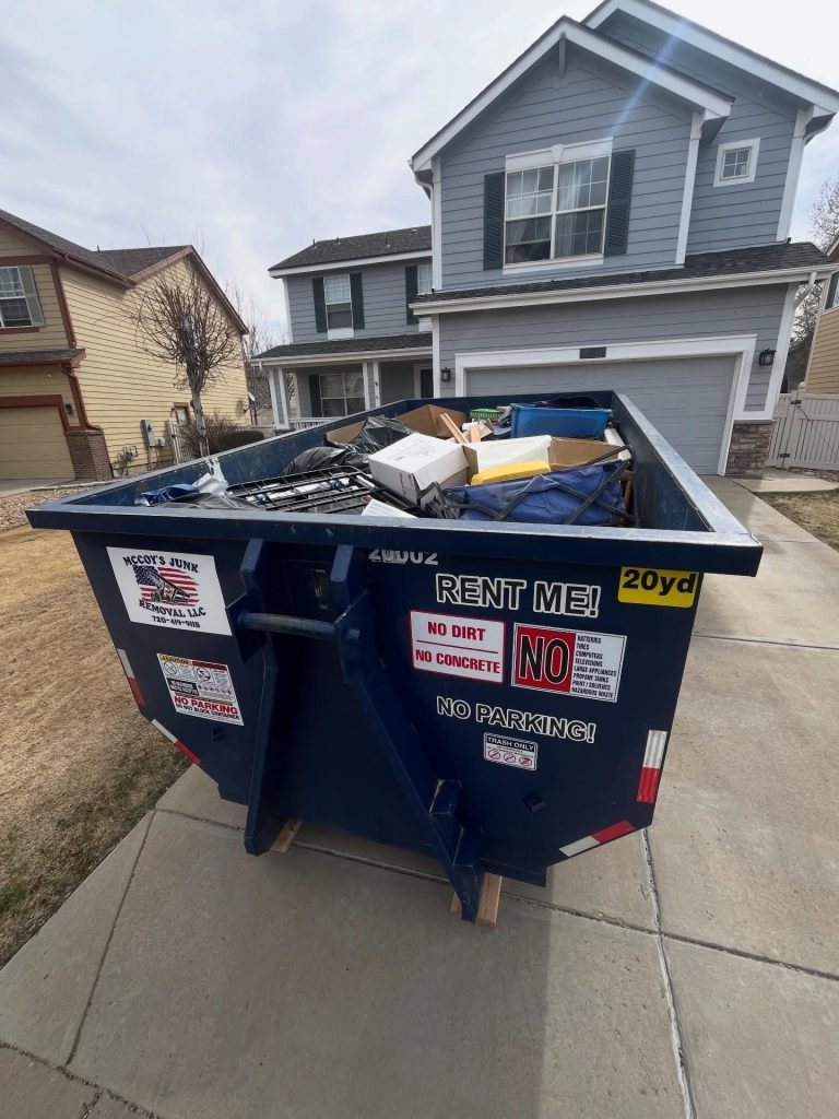 A dumpster from McCoy dumpsters that is full sitting in a driveway.